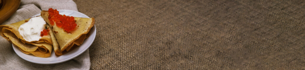 thin pancakes with red caviar on gray canvas napkin. The concept of Russian carnival Maslenitsa. space for text, banner