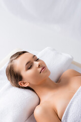 Obraz na płótnie Canvas woman with closed eyes lying on massage table in spa salon