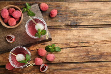 Flat lay composition with lychee cocktail on wooden table, space for text