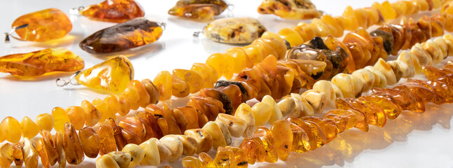 Sparkling yellow and orange Baltic amber jewelry close up on a white surface with reflection. Amber texture, background.  