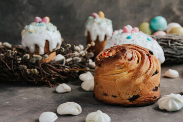 Easter cakes with white cream and painted Easter eggs on a dark gray background.
