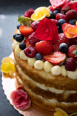 Red berries Naked cake with white cream and flowers to decor 