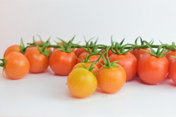 Close up. Small fresh and beneficial branch tomatoes. White background.