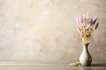 Dried flowers in vase on table against light grey background. Space for text