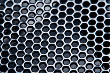 Background with dusty metal grill, black metal mesh with round holes in soft focus under high magnification