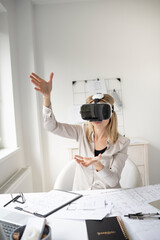 beautiful young female architect with virtual reality goggles is working in her office