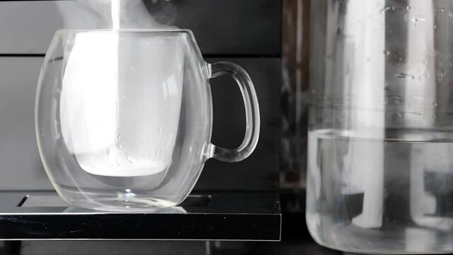 The machine is actively sprinkling the whipped cream process to make cappuccino in beautiful glass transparent cup
