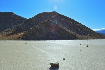 moving stones on the Racetrack Playa leaving tracks in the dry and cracked terrain in the Death Valley National Park, recflections of the sun