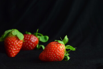 Fresh strawberries close up, black background and copy space.