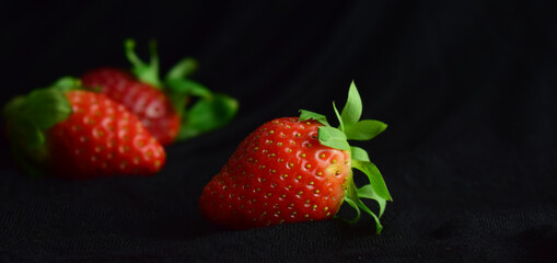 Fresh strawberries close up, black background and copy space.