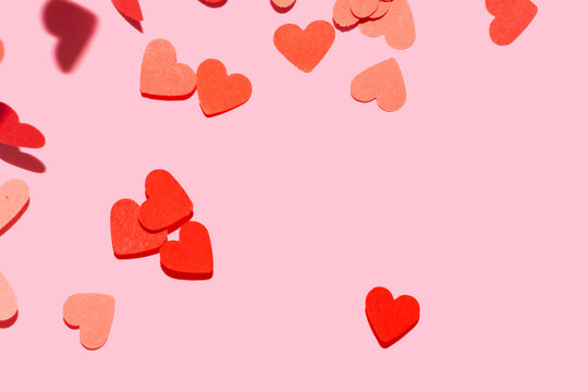 heart shape flying confetti on a pink background for valentines day