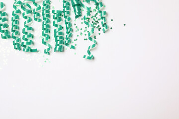 Turquoise serpentine streamers and confetti on white background, top view