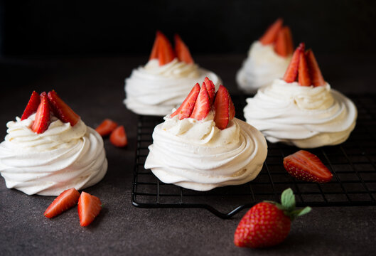 Anna Pavlova cake with cream and fresh strawberries on a dark background