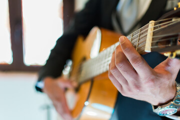 Foto de hombre sentado inclinado sostiene guitarra acústica instrumental tocando canción 