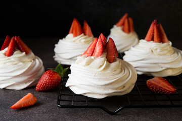 Anna Pavlova cake with cream and fresh strawberries on a dark background,