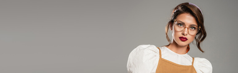 stylish woman with red lips looking at camera isolated on grey, banner