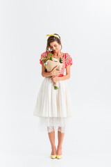 stylish woman in retro clothes holding bouquet on white