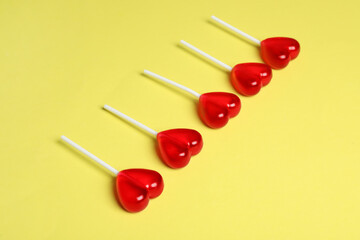 Sweet heart shaped lollipops on yellow background. Valentine's day celebration