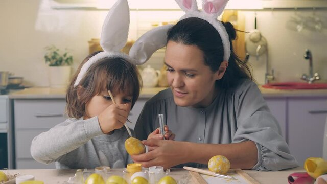 Happy Easter Holiday. Beautiful mother and daughter paint and decorate the egg for the spring traditional dinner at home