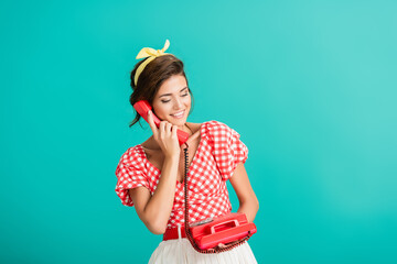 happy pin up woman talking on retro phone isolated on turquoise