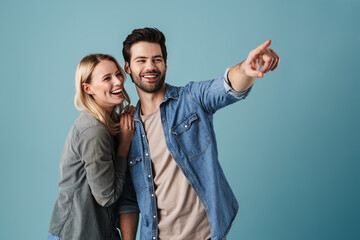 Young laughing man and woman looking and pointing finger aside