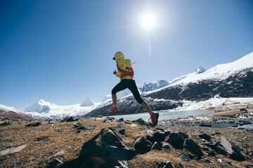 Woman trail runner cross country running in winter mountains