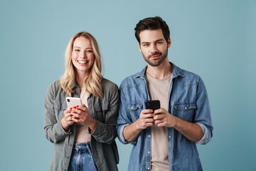 Young happy man and woman smiling and using mobile phones
