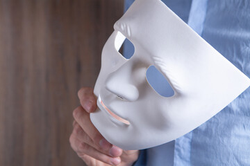 Businessman holding white mask in his hand - obrazy, fototapety, plakaty