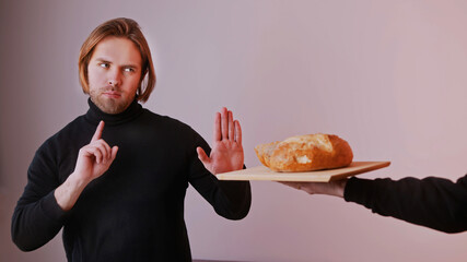 Young caucasian man on low card diet refusing to take bread offered to him. High quality photo