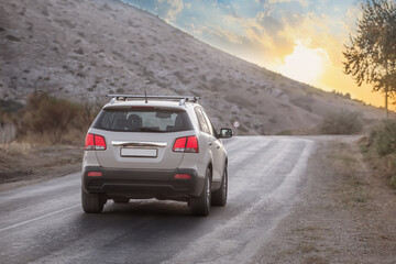 Fototapeta na wymiar SUV moves along a mountain road at sunrise