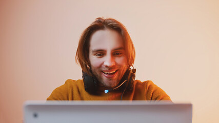 Portrait of young man with headphones winning the game. Game playing on laptop. High quality photo