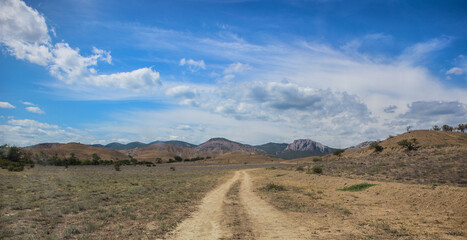 Panorama with a dirt road to the mountain range