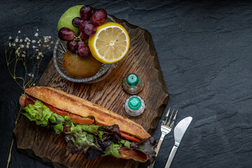 A delicious Smoked salmon sesame bread sandwich with Fresh fruit on a wooden plate.