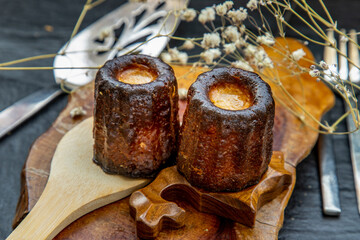 Cannelés (Canelés) de Bordeaux Recipe is a small pastry with rum and vanilla on a wooden plate.