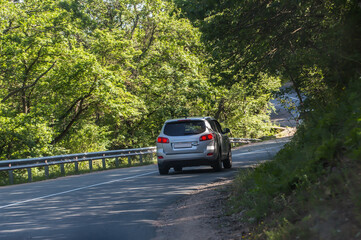 Car moves along winding road in the forest