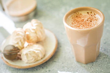 A drink in a ceramic glass and a cake on the table. Nice breakfast.