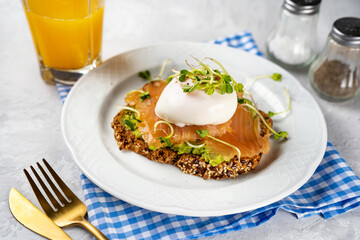 Healthy and delicious toast with avocado, salmon, poached egg and microgreens for breakfast or branch. Home comfort cooking. Pescatrian diet. Brain food. Omega 3 fats.