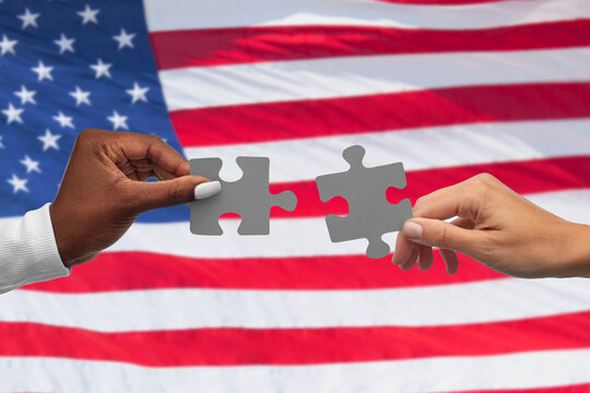 communication, cooperation and people concept - black and white hands matching pieces of puzzle over flag of united states background