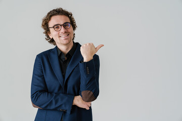 Joyful handsome man in eyeglasses smiling and pointing finger aside