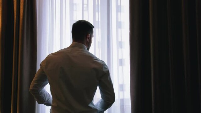 Businessman in luxury room of hotel. Successful businessman looking into window at his hotel