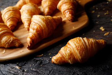 freshly baked croissants set of delicious fresh in wax paper plates on wooden dark table. French breakfast