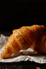 freshly baked croissants set of delicious fresh in wax paper plates on wooden dark table. French breakfast. top view Copy space.