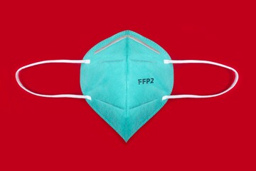 Green FFP2 n95 protective face mask on red background. Protection and prevention against coronavirus, covid-19 and other viruses.