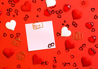 Square sheet for notes with a paper clip in shape of a letter and a heart. Decor of couples in love with hearts on a red background. Valentine's Day, message, greeting, declaration of love. Copy space