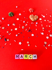 Colorful wooden cube beads with letters on red festive background, word "march".Holiday concept. Spring time. Greeting card. 8 March.  Happy Women's Day.
