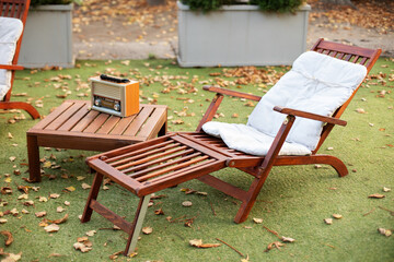 Wooden chairs in autumn garden. Vintage radio on table. Two deckchairs on green summer lawn on...