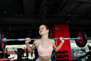 Athletic girl in sportswear performs exercises with barbell, dumbbells. Fitness, healthy lifestyle