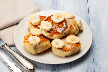 Homemade pancakes with raisins poured on with condensed milk and served with cutted bananas