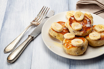 Homemade pancakes with raisins poured on with condensed milk and served with cutted bananas