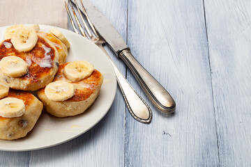 Homemade pancakes with raisins poured on with condensed milk and served with cutted bananas